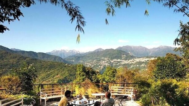 A terrace with a table and benches overlooking a mountainous landscape. - Bamboo Retreat Hotel (Gangtok)