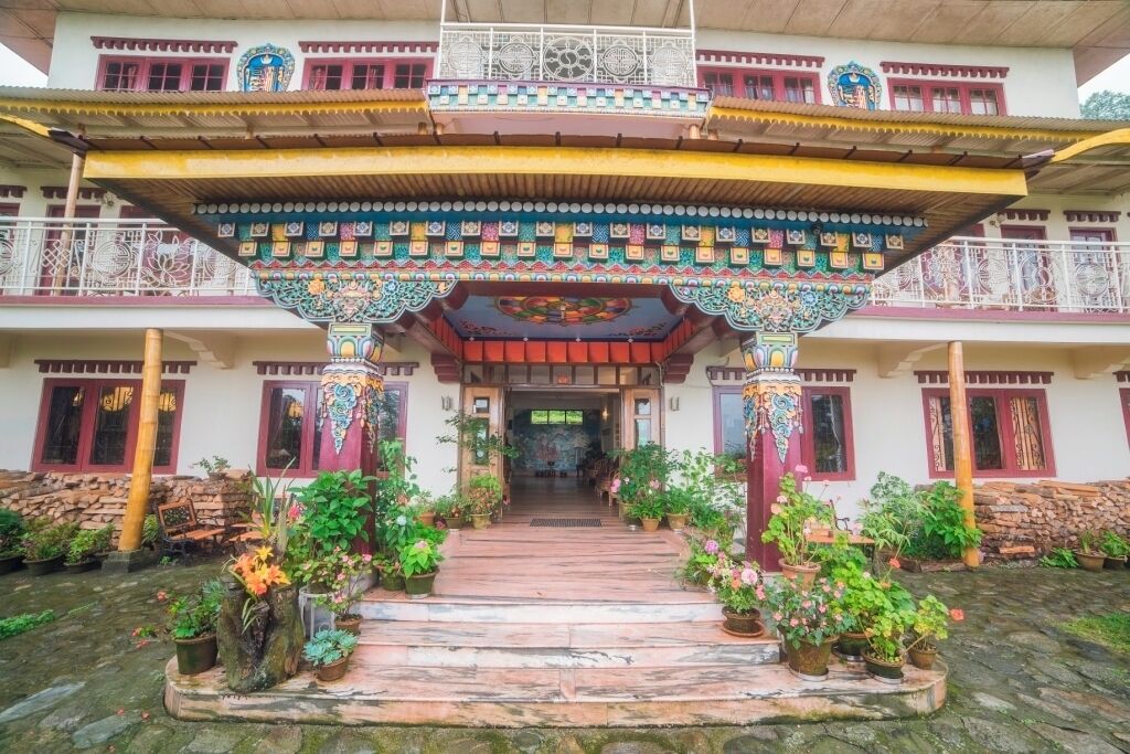 A multi-story building with a traditional architectural style, featuring a central entrance with a decorative overhang and potted plants.