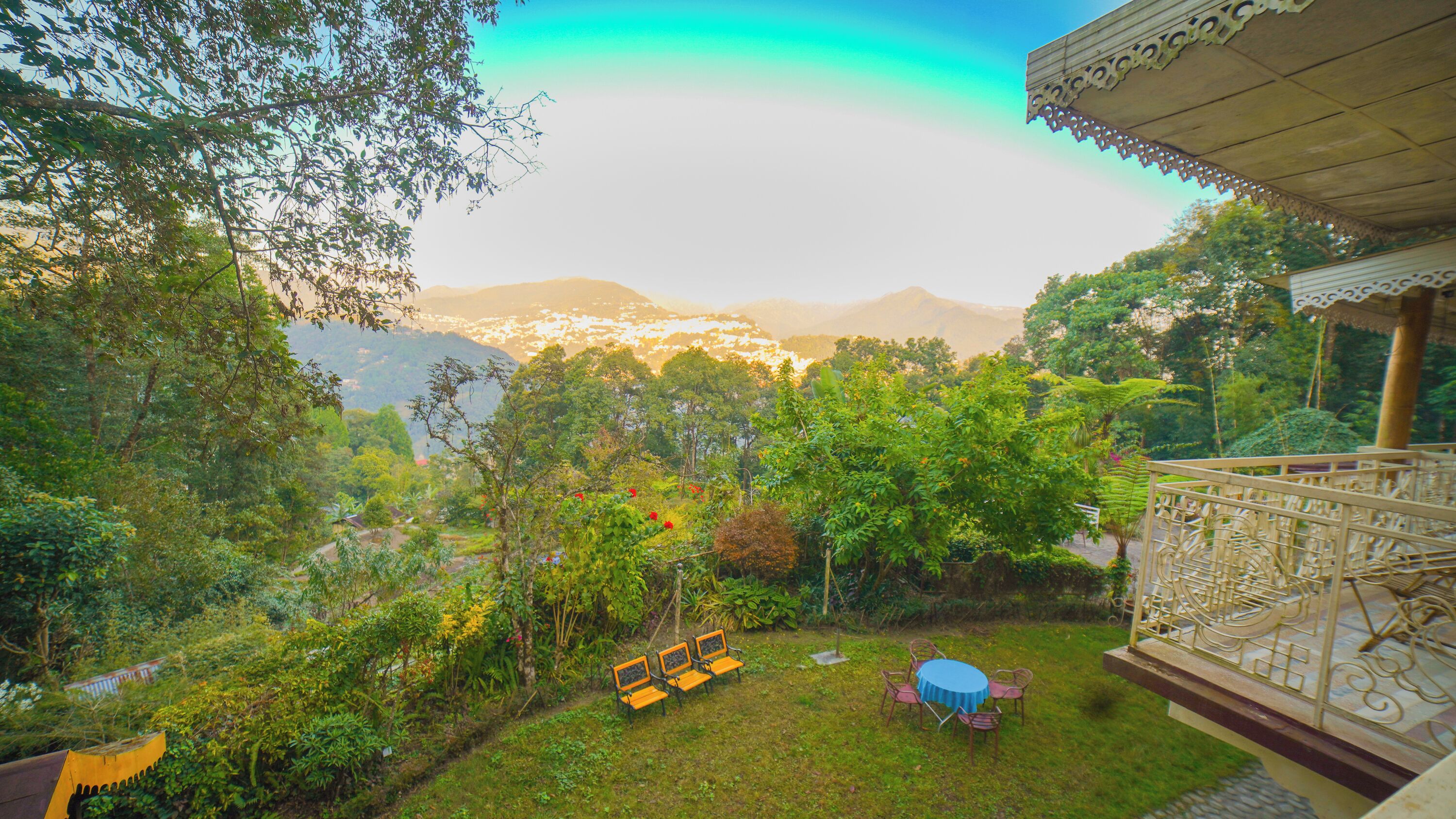 Un jardin luxuriant offrant une vue sur les montagnes lointaines, agrémenté d’un belvédère et de coins salon aménagés à l’extérieur.
