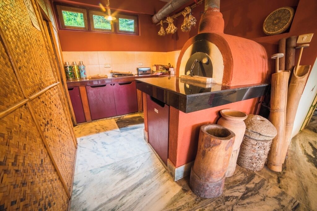 A kitchen with a wood-fired oven, a marble countertop, and rustic pottery.