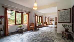 A spacious room with large windows, a marble floor, and a hanging light fixture. - Bamboo Retreat Hotel (Gangtok)