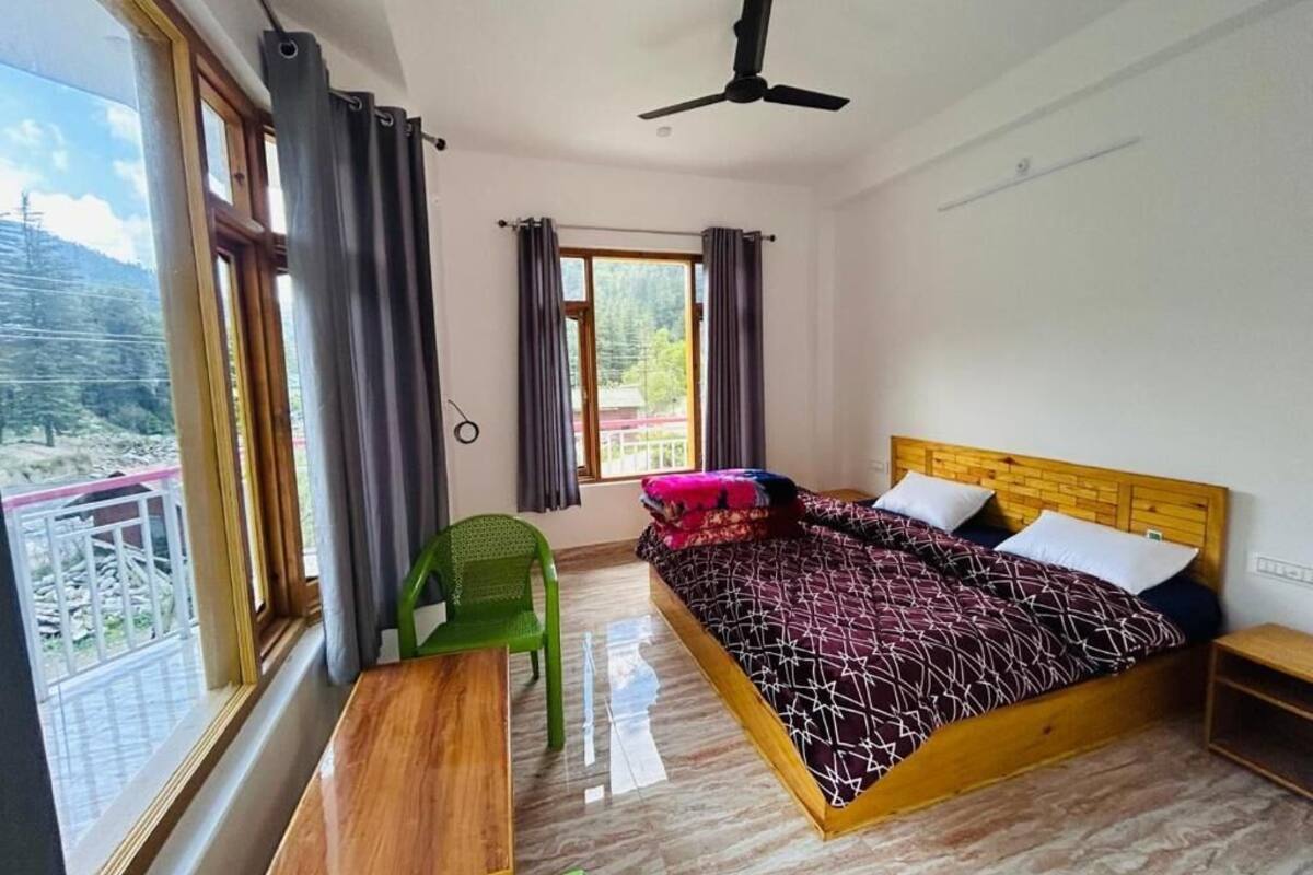 A bedroom with a bed, a desk, a chair, a window with curtains, and a ceiling fan.