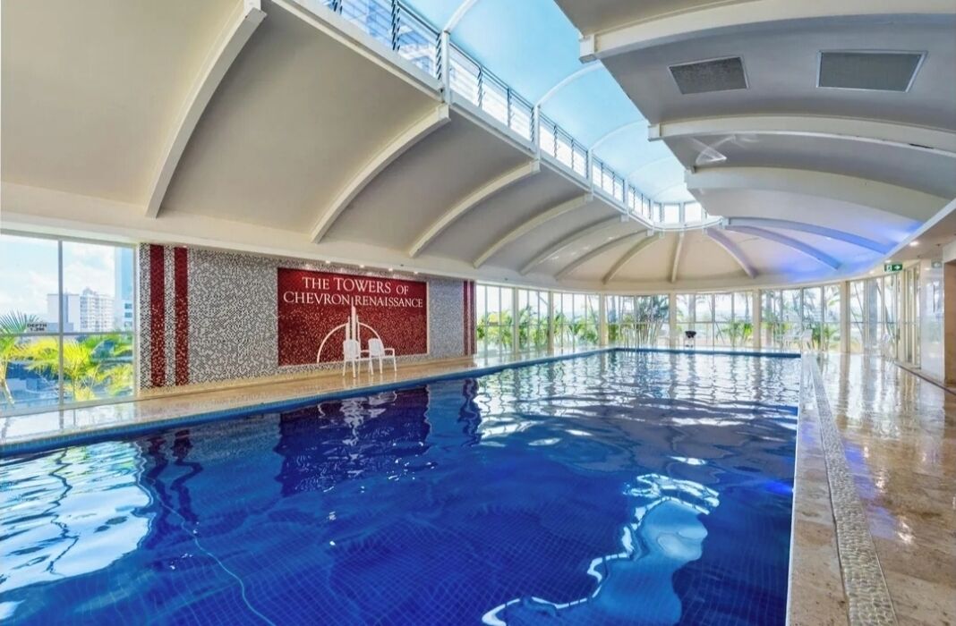 En indendørs swimmingpool med udsigt til byens skyline, et skilt der siger "The Towers of Chevrons Renaissance", og et glastag.