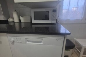 Una cucina con un forno a microonde, un espositore per piatti e una lavastoviglie.