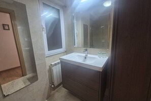 A bathroom with a white sink, a mirror, a window, and a radiator. - 1A169 3-Bedroom Apartment by R2R (Gijón)