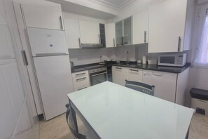 Una cucina moderna con mobili bianchi, forno a incasso, microonde e un tavolo da pranzo.