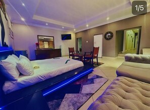 Ein modernes Hotelzimmer mit einem Bett, einer Couch, einem Fernseher und einem Essbereich.