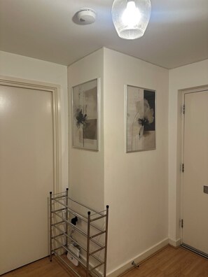 Habitación con paredes blancas, una lámpara de techo y dos cuadros abstractos enmarcados.