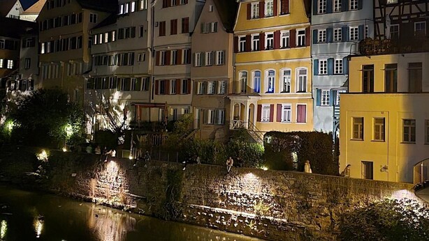 Una hilera de edificios europeos tradicionales a orillas de un río, de noche.