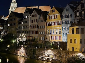 Une rangée de bâtiments européens traditionnels le long d’une rive, de nuit.