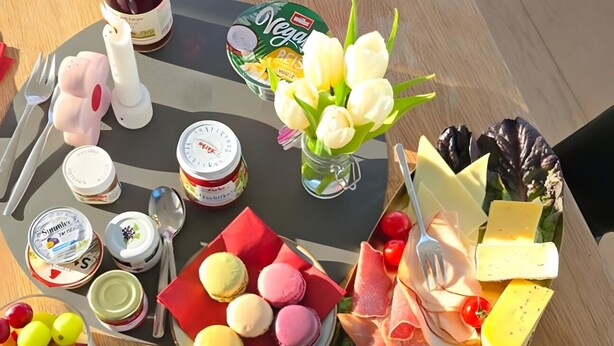 A table with various food items, including cheese, macarons, and a bottle of wine. - City-Adjacent Guest Room in Esi’s Penthouse in Tübingen (Tübingen)