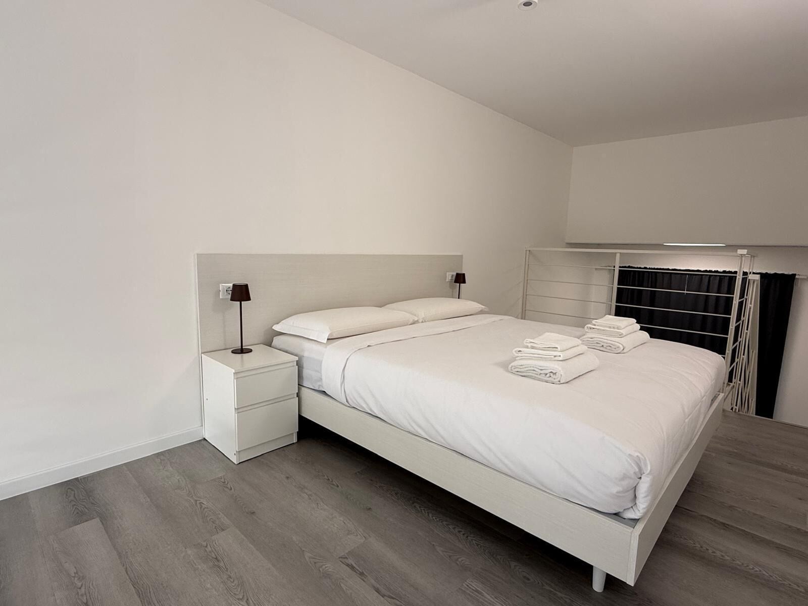 A modern bedroom with a single bed, a nightstand, a bedside table, and a built-in wardrobe.