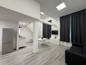 A modern apartment with a kitchen, dining area, and living space, featuring a staircase, a flat-screen TV, and a black sofa. - Viva Residence (Calderara di Reno)