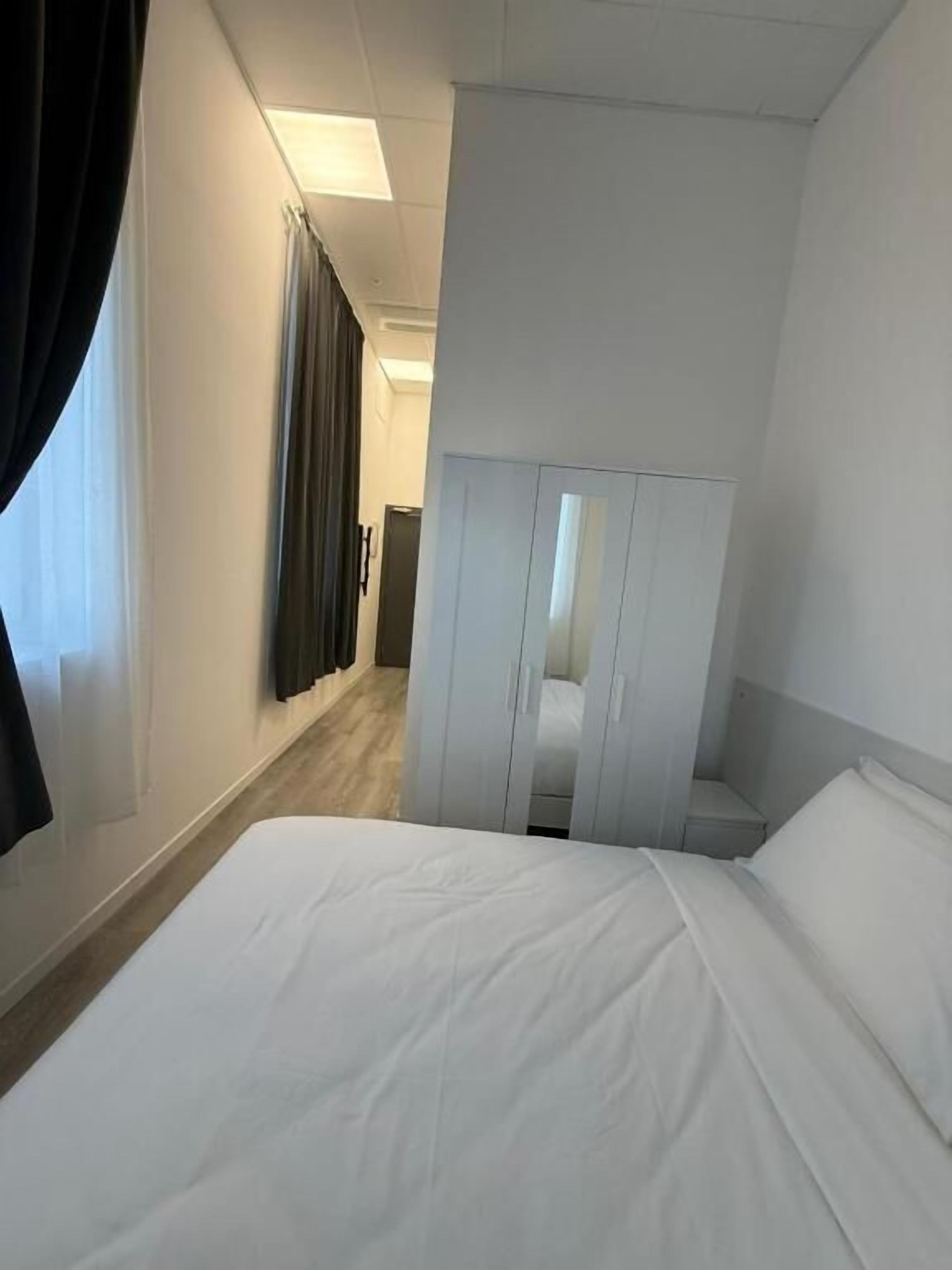 Una habitación de hotel con una cama, un armario y una puerta que da a otra habitación.