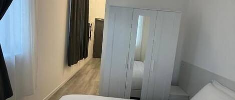 A hotel room with a bed, a wardrobe, and a door leading to another room.