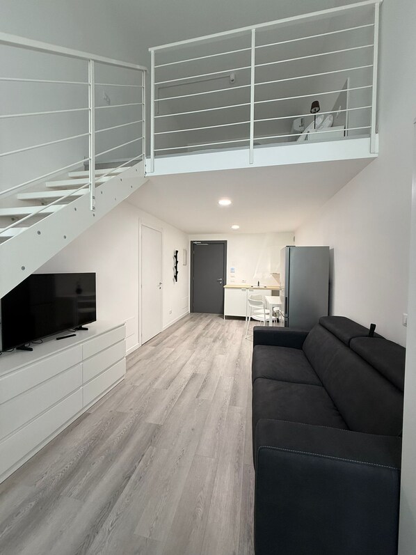 A modern apartment with a loft bedroom, a dining area, and a living room with a sofa. - Viva Residence (Calderara di Reno)