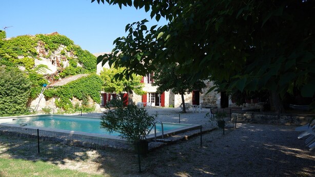 Un espace piscine agrémenté d’un mur en pierre, d’un petit arbre et d’un banc.