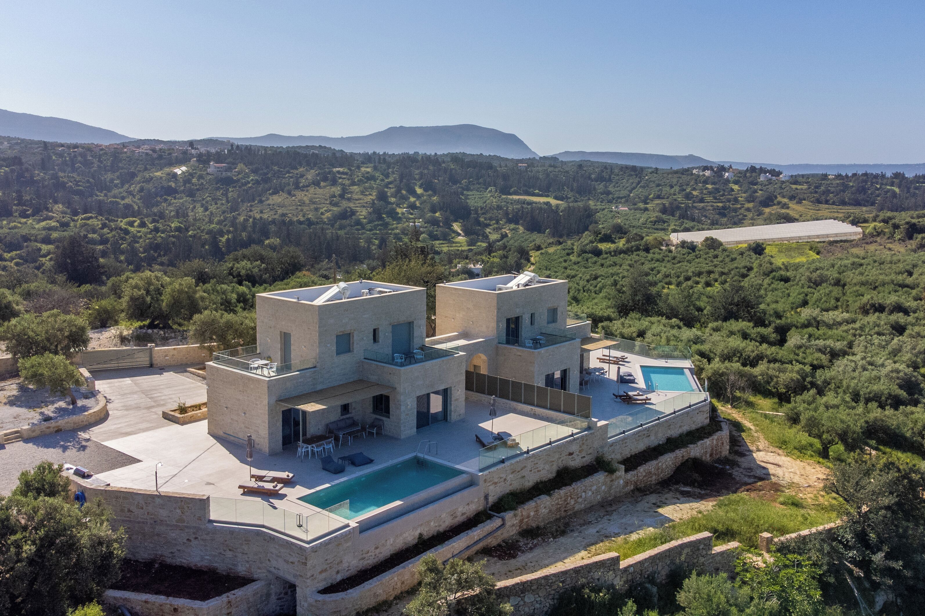 Una villa moderna con piscina, varios niveles y vistas del paisaje circundante.