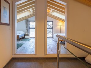 Ein modernes Interieur mit einer Treppe zu einem Dachzimmer mit Dachfenster, einem sichtbaren Bett und Blick ins Freie.