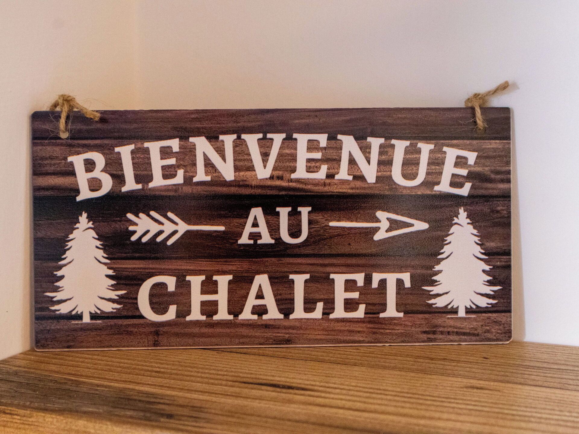 A wooden sign with 'BIENVENUE AU CHALET' and tree symbols.
