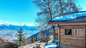 Eine Holzhütte mit Blick auf schneebedeckte Berge.