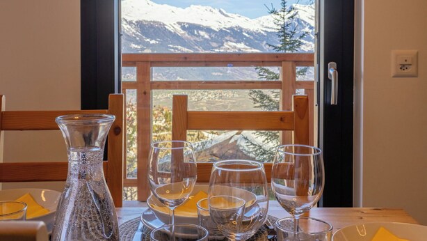 Ein Tisch mit Blick auf schneebedeckte Berge durch ein Fenster.