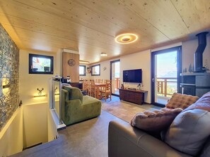 A cozy living room with a fireplace, a television, and a dining area with wooden furniture. - Cosy apartment in villa for 8 people with WIFI, TV and patio (Basse-nendaz)