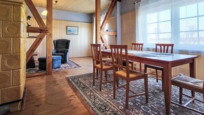 A dining area with a wooden table and chairs, a patterned rug, and a chandelier.