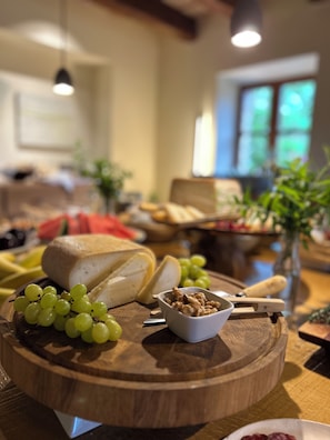 Tábua de madeira com queijo, uvas e nozes sobre uma mesa.