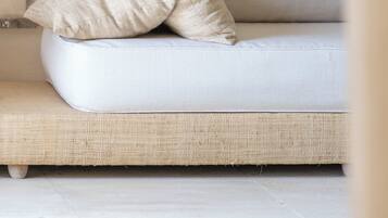 Un sofá blanco con dos almohadas color beige frente a una pared lisa.