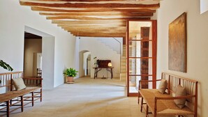 Un pasillo amplio con bancos de madera, una escalera y un cuadro grande en la pared.