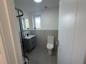 Une salle de bain avec des toilettes, un lavabo et une fenêtre.
