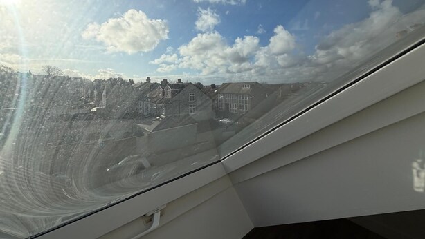 Blick aus einem Flugzeugfenster bei blauem Himmel und vereinzelten Wolken.