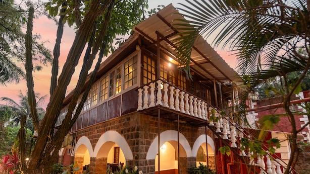 A two-story building with a balcony, surrounded by lush greenery and potted plants. - Sherbaug Nature Park & Resort (Panchgani)