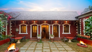A brick building with a tiled patio, outdoor seating, and fire pits. - Sherbaug Nature Park & Resort (Panchgani)