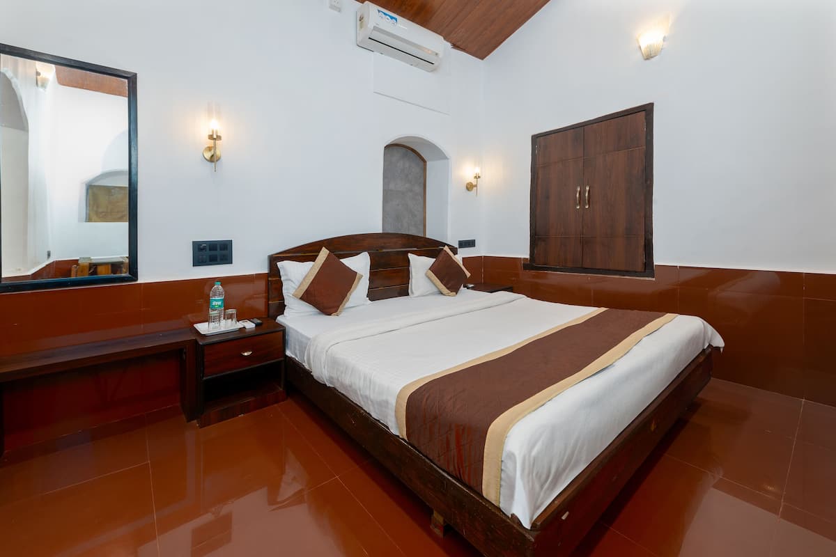 A hotel room with a wooden bed, a nightstand, a mirror, and a wardrobe.