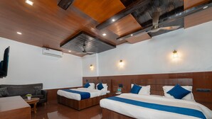 A hotel room with two beds, a sofa, a wooden coffee table, and a ceiling fan. - Sherbaug Nature Park & Resort (Panchgani)