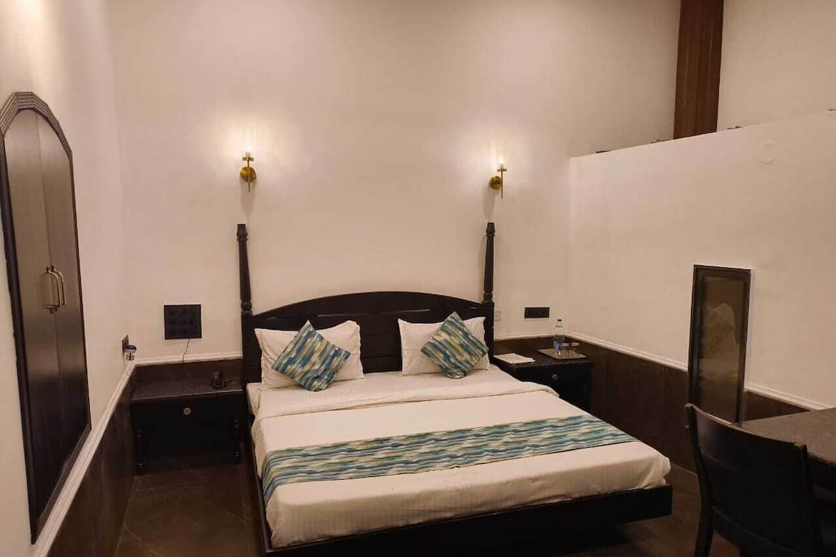 A bedroom with a bed, bedside tables, a desk, and a chair.