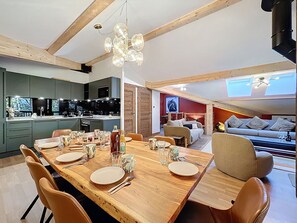 A modern kitchen with dark cabinets and a dining area with a wooden table set for four. - Ceiba - Les Gets - Near the center (Les Gets)