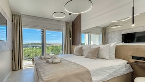 A modern hotel room with a large bed, a TV, and a balcony with a city view.