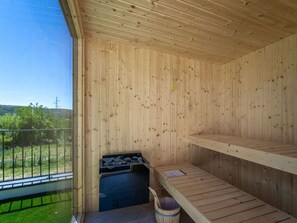 Sala de sauna com paredes de madeira, um banco e um assento.