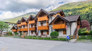 Une rangée de bâtiments de style chalet, dotés de balcons, un chemin piétonnier et une vue sur les montagnes en arrière-plan.