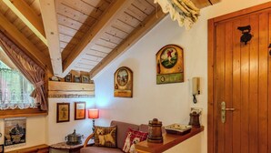 Une pièce chaleureuse avec un plafond en bois, une porte en bois, un canapé, une table et divers éléments de décoration murale, notamment des tableaux encadrés et une lampe.