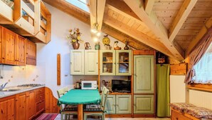Une cuisine avec des meubles en bois, une table à manger avec des chaises, un four à micro-ondes, une cuisinière et une fenêtre avec des rideaux.