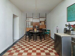 Eine kompakte Küche mit Schachbrettboden, ein Essbereich mit rundem Tisch und eine Küchenzeile mit Toaster.
