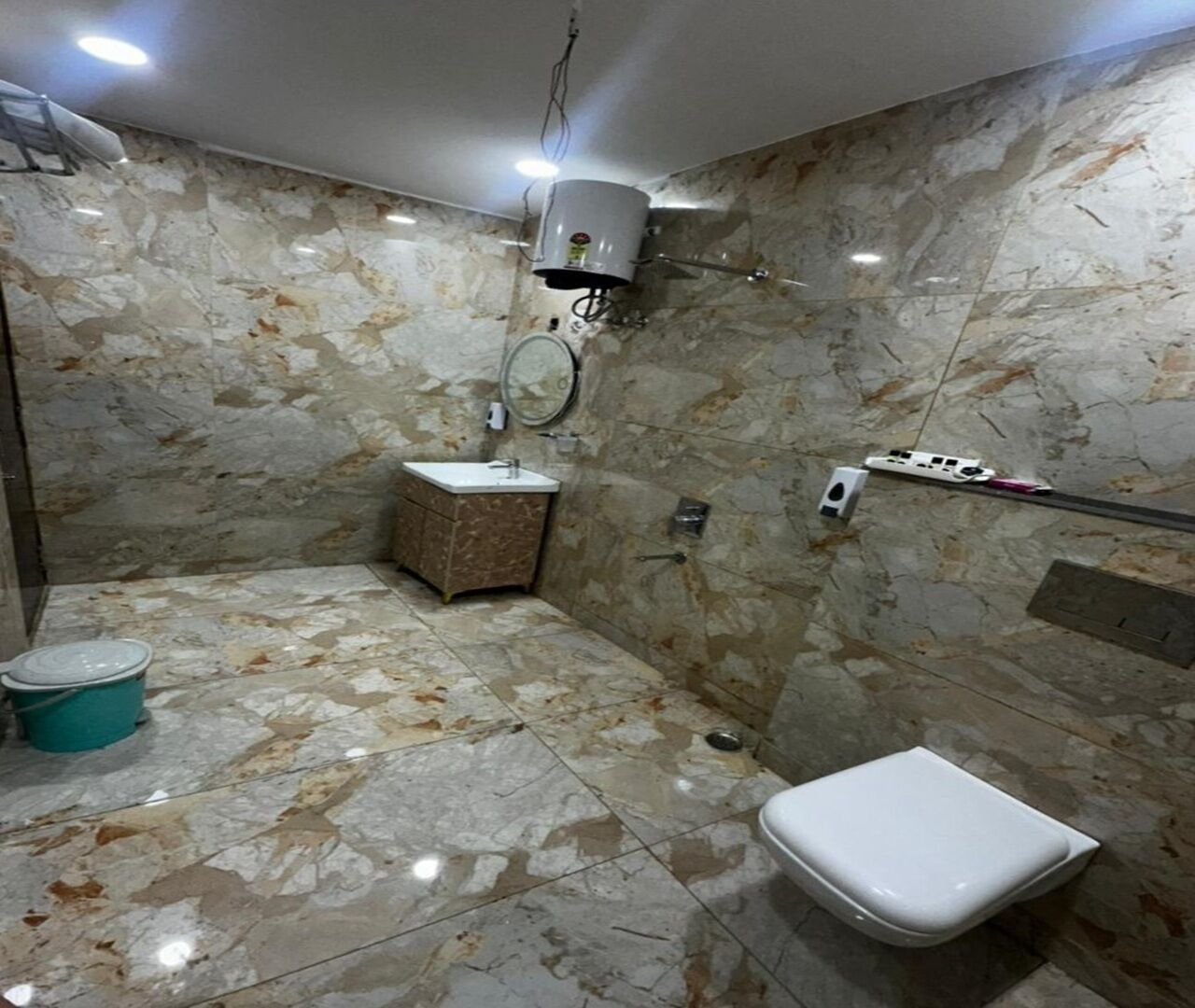 Un bagno con pavimento in marmo, un WC, un lavandino e una zona doccia.