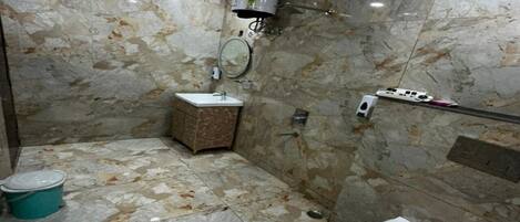 Un bagno con pavimento in marmo, un WC, un lavandino e una zona doccia.