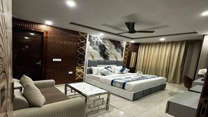 A modern hotel room with a bed, a sofa, a coffee table, and a ceiling fan.