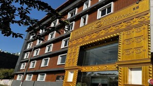 A hotel with a modern facade, multiple windows, and a sign indicating it is a hotel and bank.