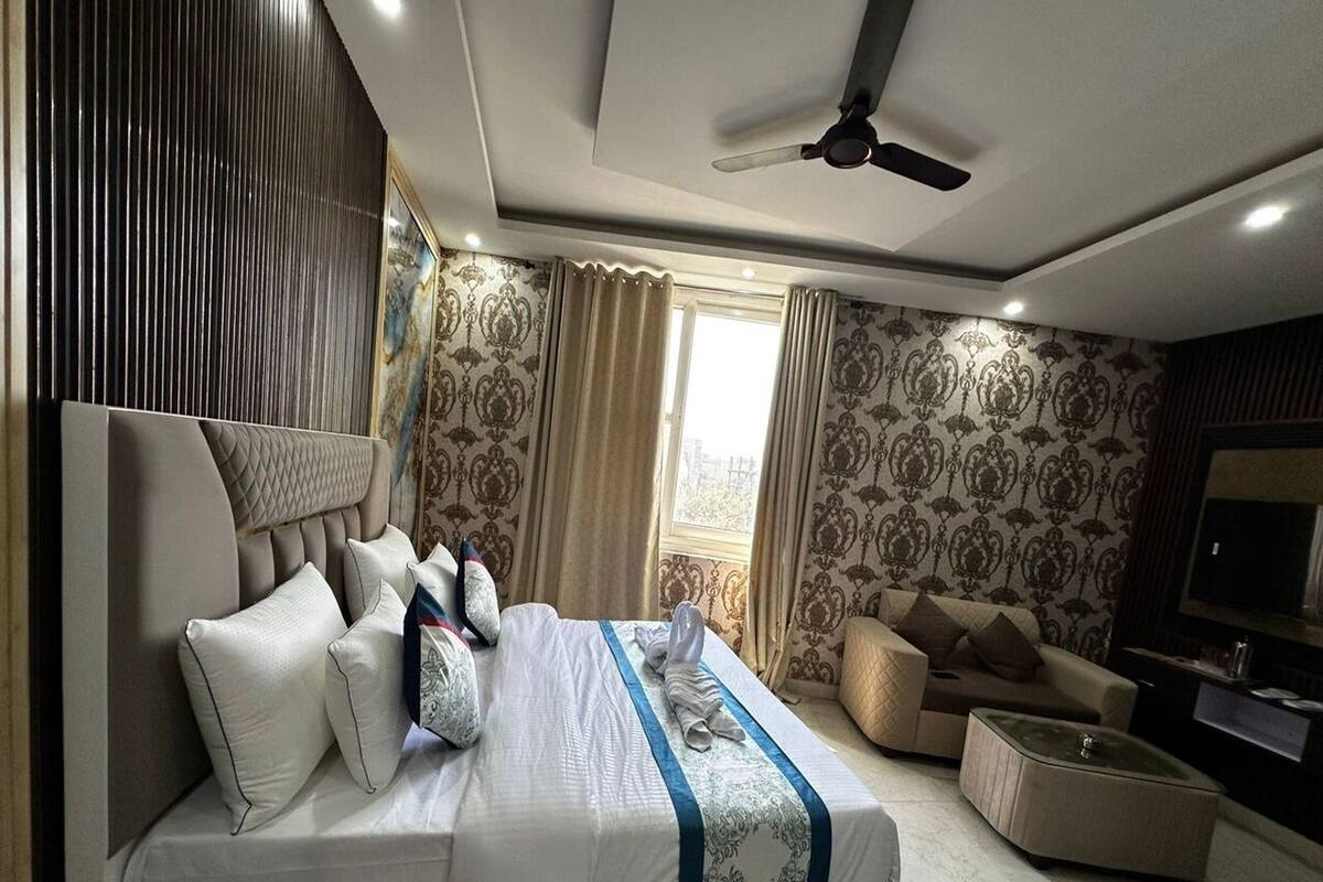 Une chambre d’hôtel moderne équipée d’un grand lit, d’un canapé, d’une télévision et d’un ventilateur de plafond.